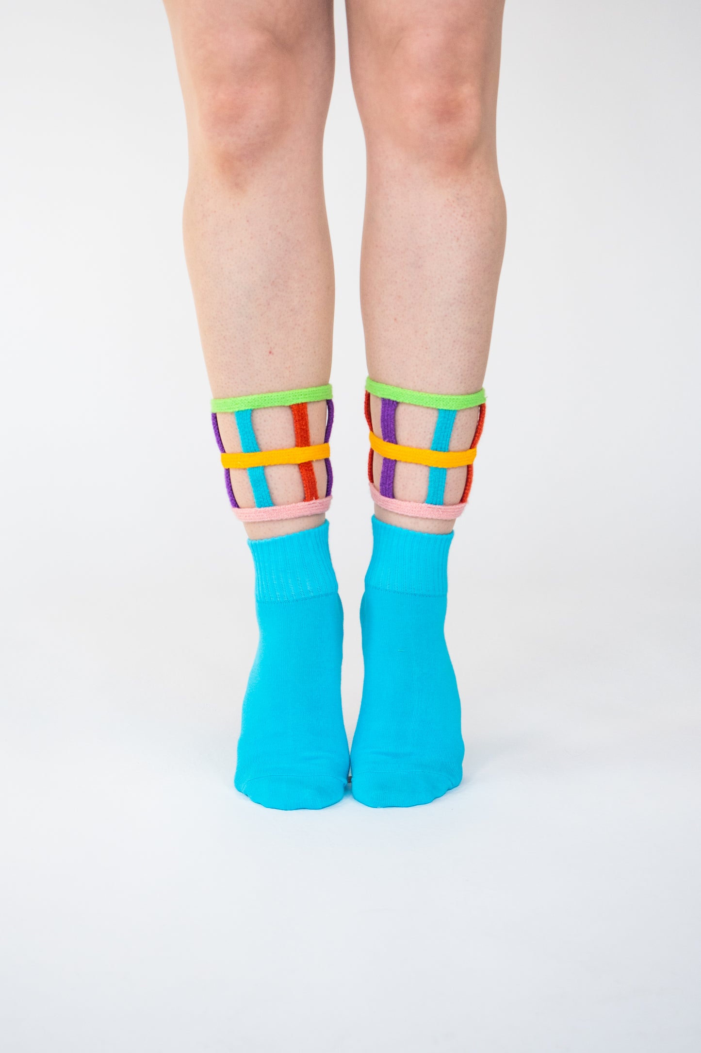 Atypical Attire socks are unique socks and luxury socks. These bright multicoloured colour cuff socks are made from cotton. They have handmade components. These are two-part light and bright blue socks with purple, pink, green, blue and yellow strips.