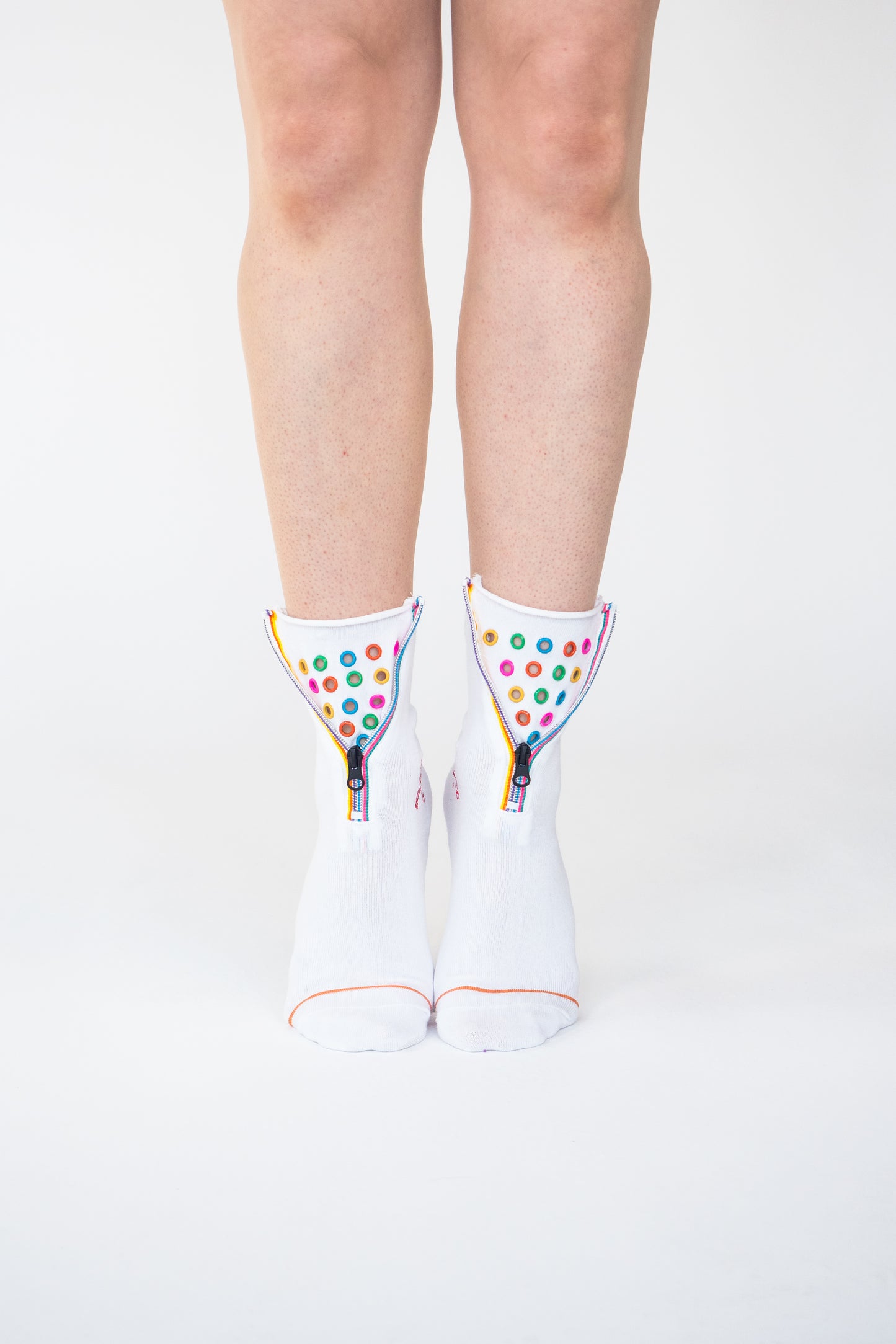 Colour Hoop Zipper socks. Atypical Attire socks are unique socks and luxury socks. These white cotton socks contain multicoloured eyelets and colourful striped zips with a zipper for a fun summer style and are worn with converses and jeans. They can be worn zipped up or zipped down. Colours of eyelets include pink, orange, yellow, blue, red, green and purple.